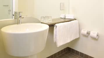 A bathroom with a sink, mirror, towel rack, and toilet paper.