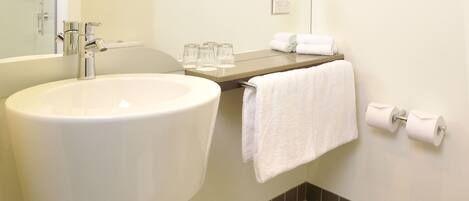 A bathroom with a sink, mirror, towel rack, and toilet paper.