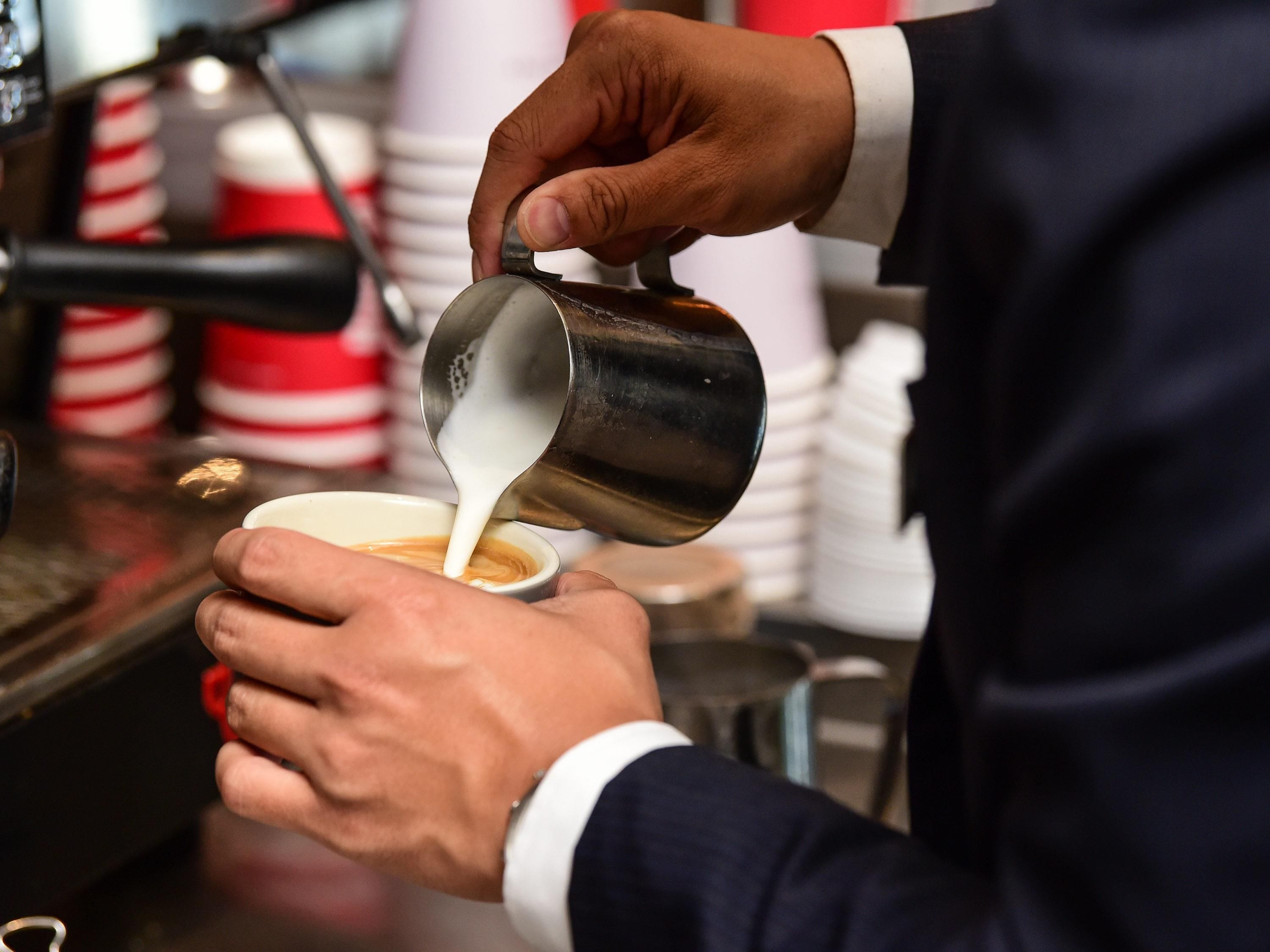 A person pouring milk into a cup.