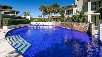 Alberca al aire libre, sombrillas en la alberca y camastros