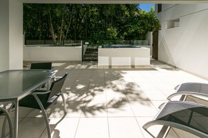 Une terrasse extérieure moderne, dotée d’une table et de chaises en verre, d’une petite piscine et offrant une vue sur une végétation luxuriante.
