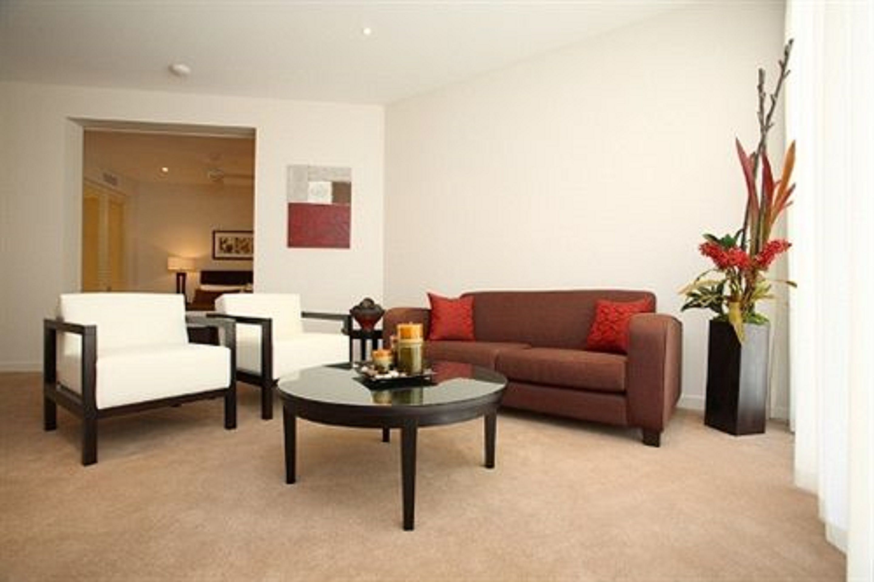 A living room with a brown sofa, white armchairs, and a coffee table.
