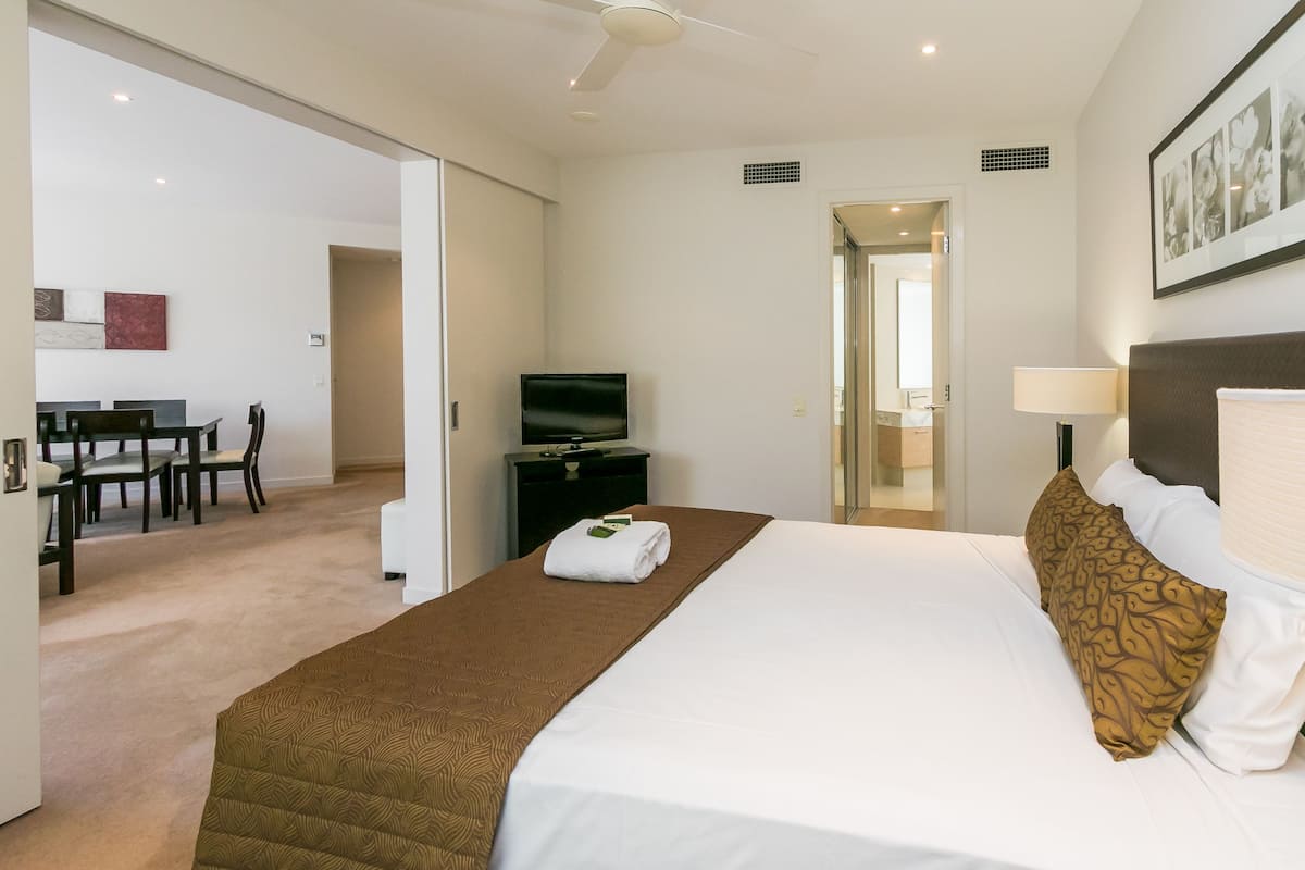 A hotel room with a bed, a TV, a desk, and a chair.