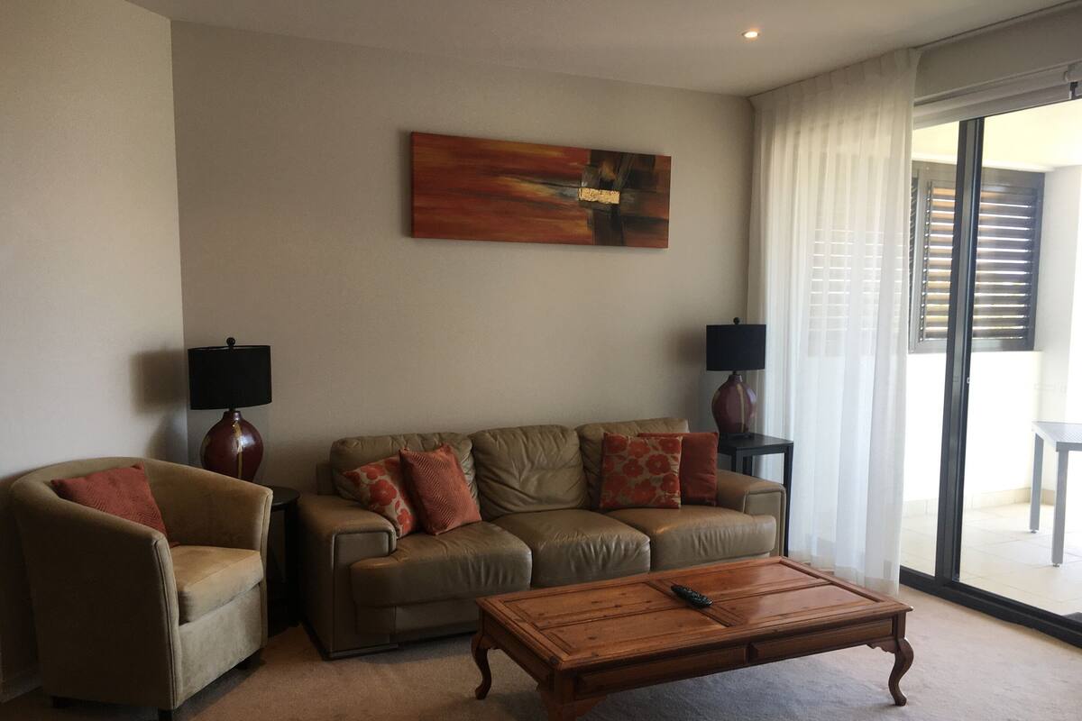 A living room with a sofa, armchairs, a coffee table, and two lamps.