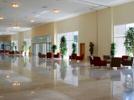 A spacious lobby with a polished floor, multiple seating areas, and large windows allowing natural light.