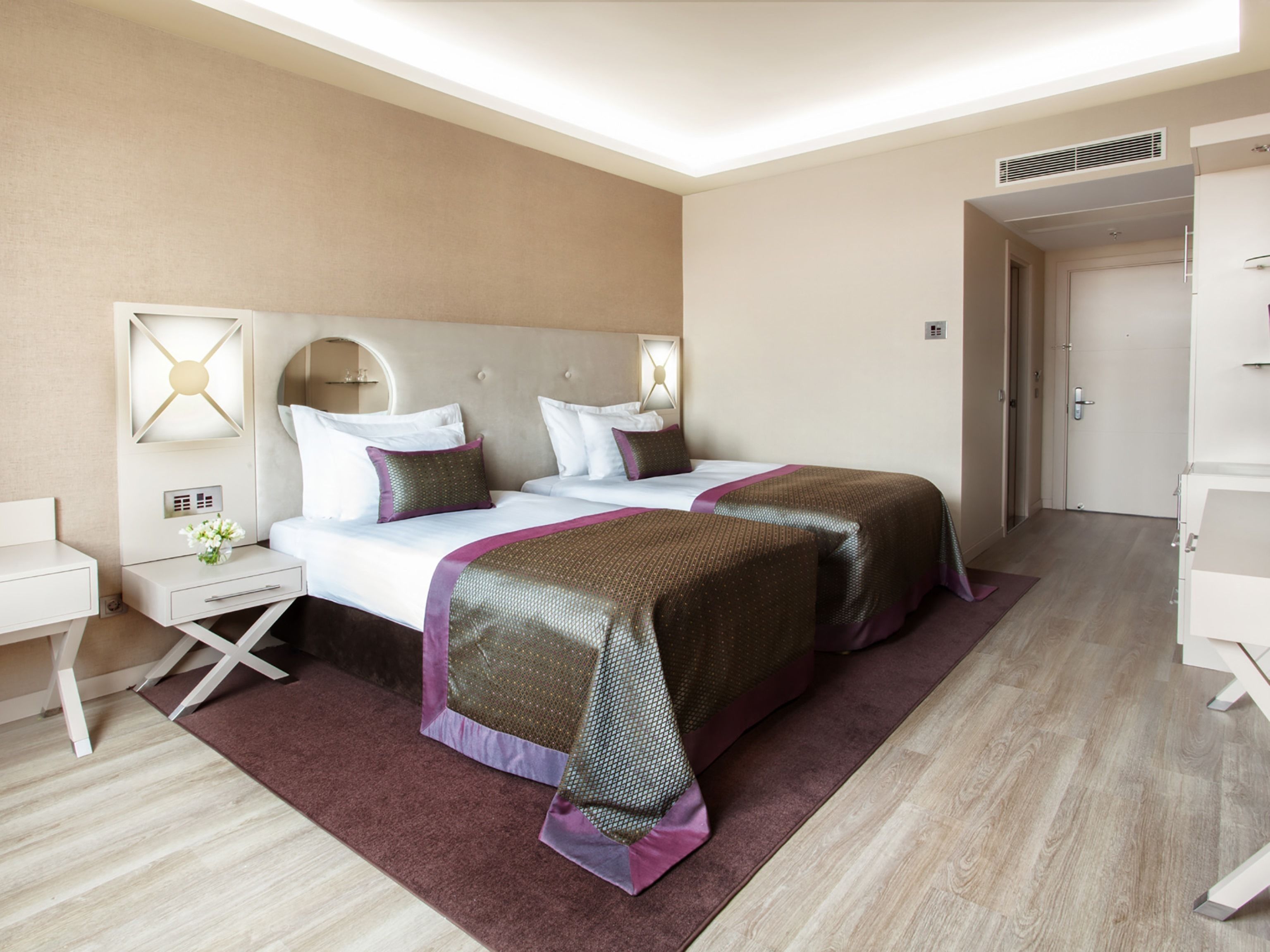 Ein Hotelzimmer mit zwei Betten, einem Nachttisch, einer Lampe und einer Tür.