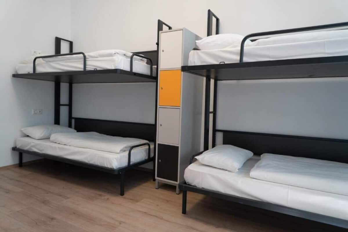 Une chambre de dortoir avec des lits superposés, une armoire et un plancher en bois.