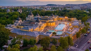 Um complexo de edifícios históricos com uma piscina central, rodeado por vegetação exuberante e arquitetura clássica.