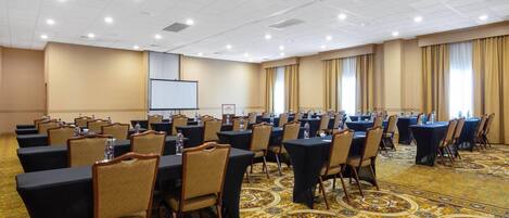 Una sala de conferencias con mesas, sillas y una pantalla para proyector.