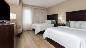 A hotel room with two beds, a desk, a television, and a window with curtains. - Hawthorn Extended Stay by Wyndham West Palm Beach Airport (West Palm Beach)