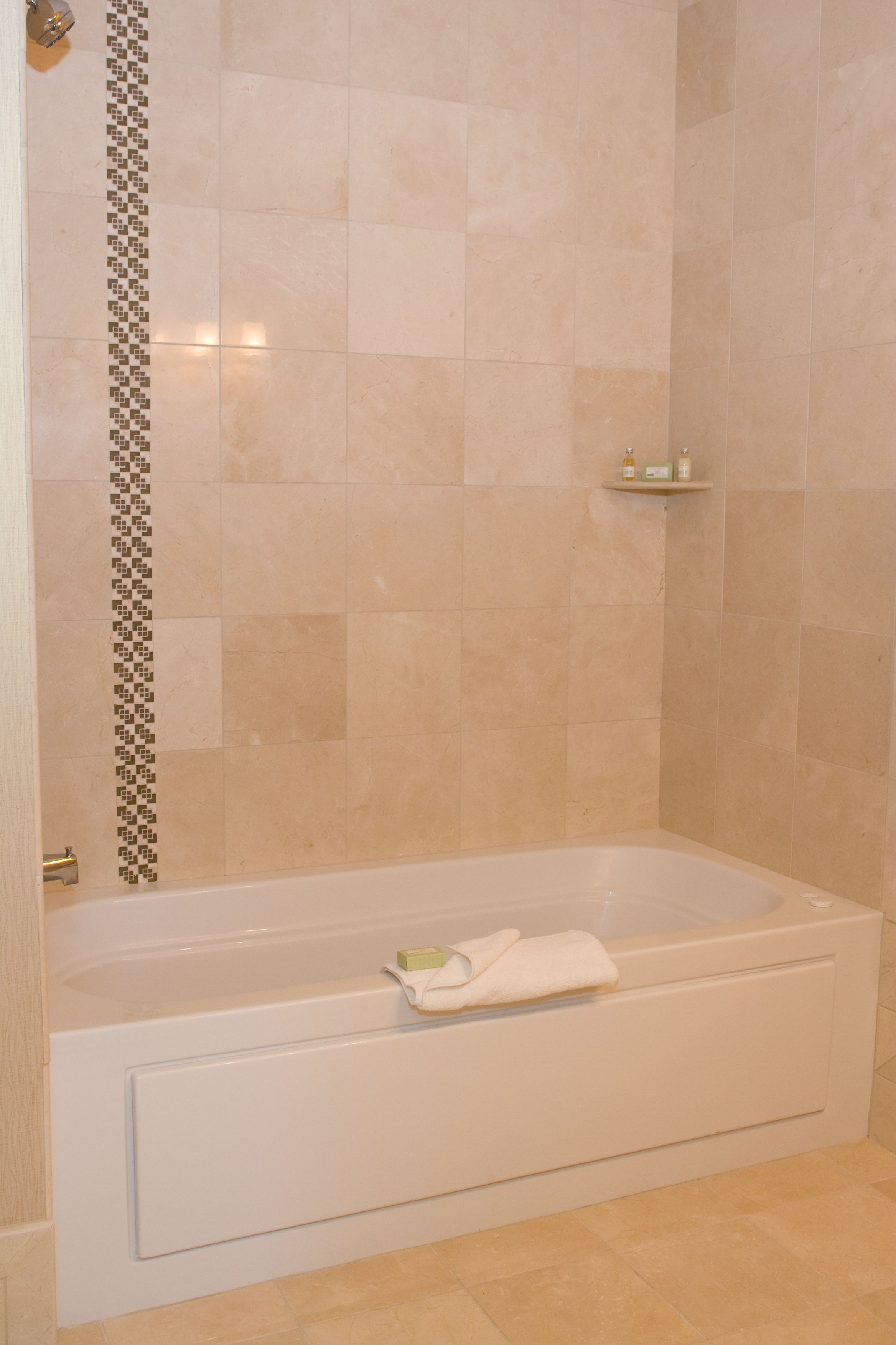 A bathroom with a bathtub, a shower area, and a shelf with toiletries.