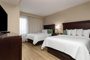 Una habitación de hotel con dos camas, un televisor, un escritorio y una lámpara.