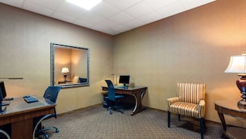 Habitación de hotel con escritorio, computadora, silla y lámpara.