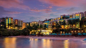 Un hotel con varias edificaciones, una playa y palmeras.