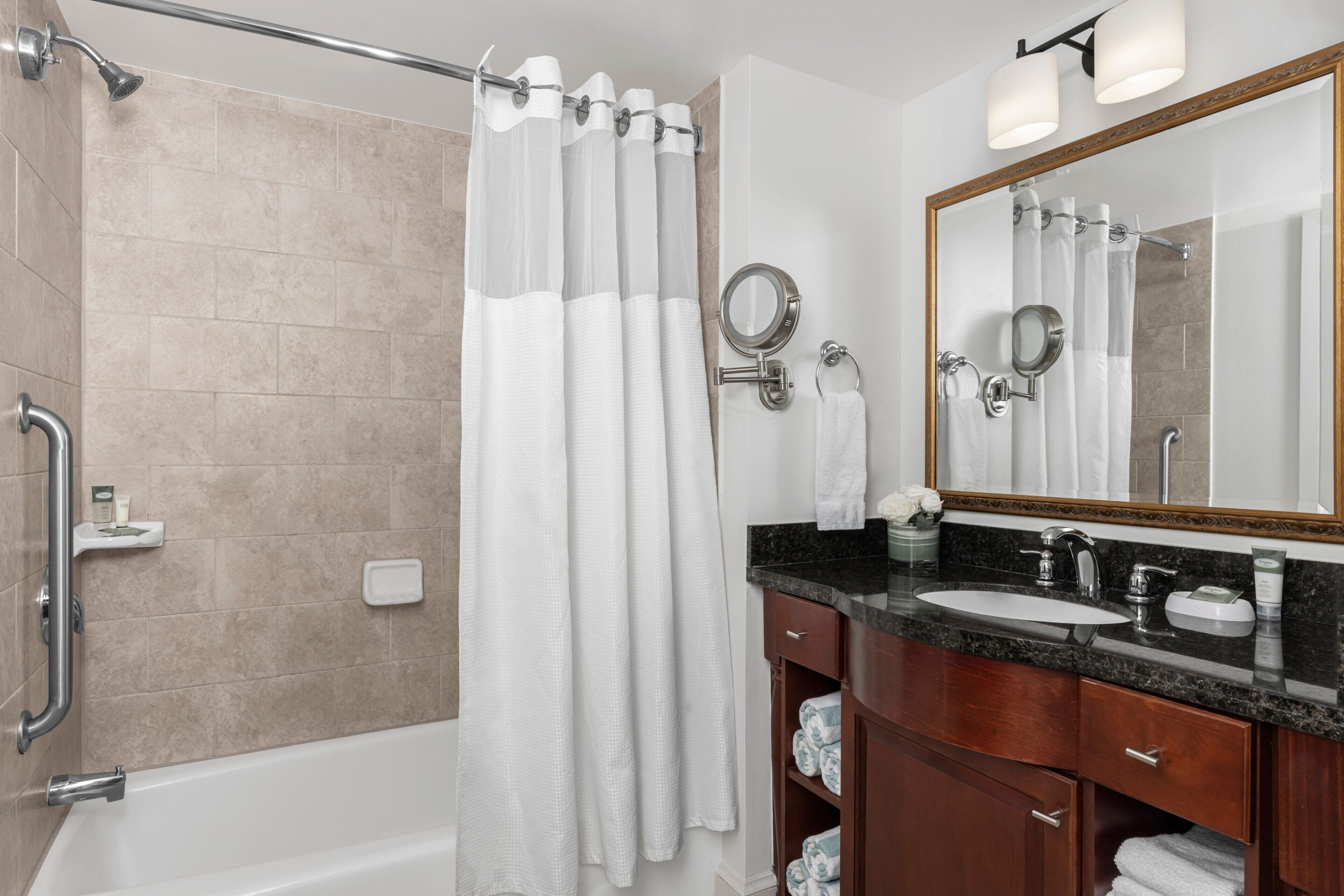 A modern bathroom with a bathtub, a shower with a glass door, a vanity with a sink and mirror, and a towel rack.