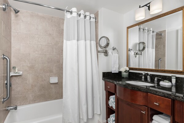 A modern bathroom with a bathtub, a shower with a glass door, a vanity with a sink and mirror, and a towel rack.