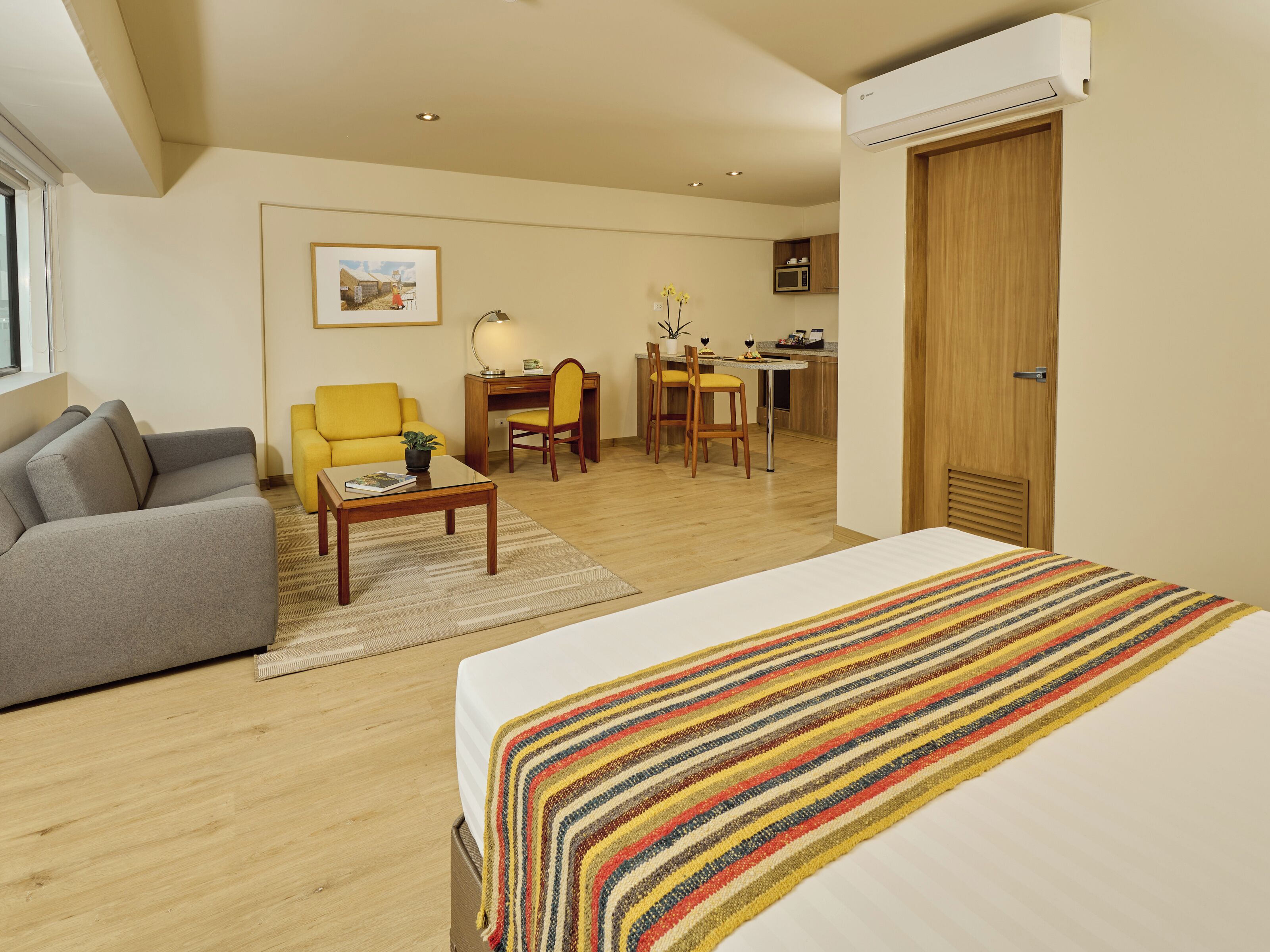 A hotel room with a bed, a sofa, a desk, and a chair.