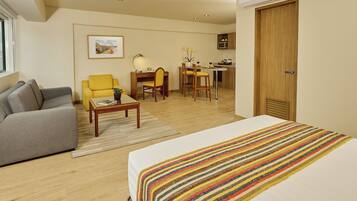 A hotel room with a bed, a sofa, a desk, and a chair.