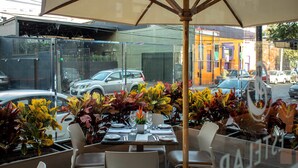 An outdoor dining area with tables set for two, surrounded by lush foliage. - Estelar Apartamentos Bellavista (Lima)