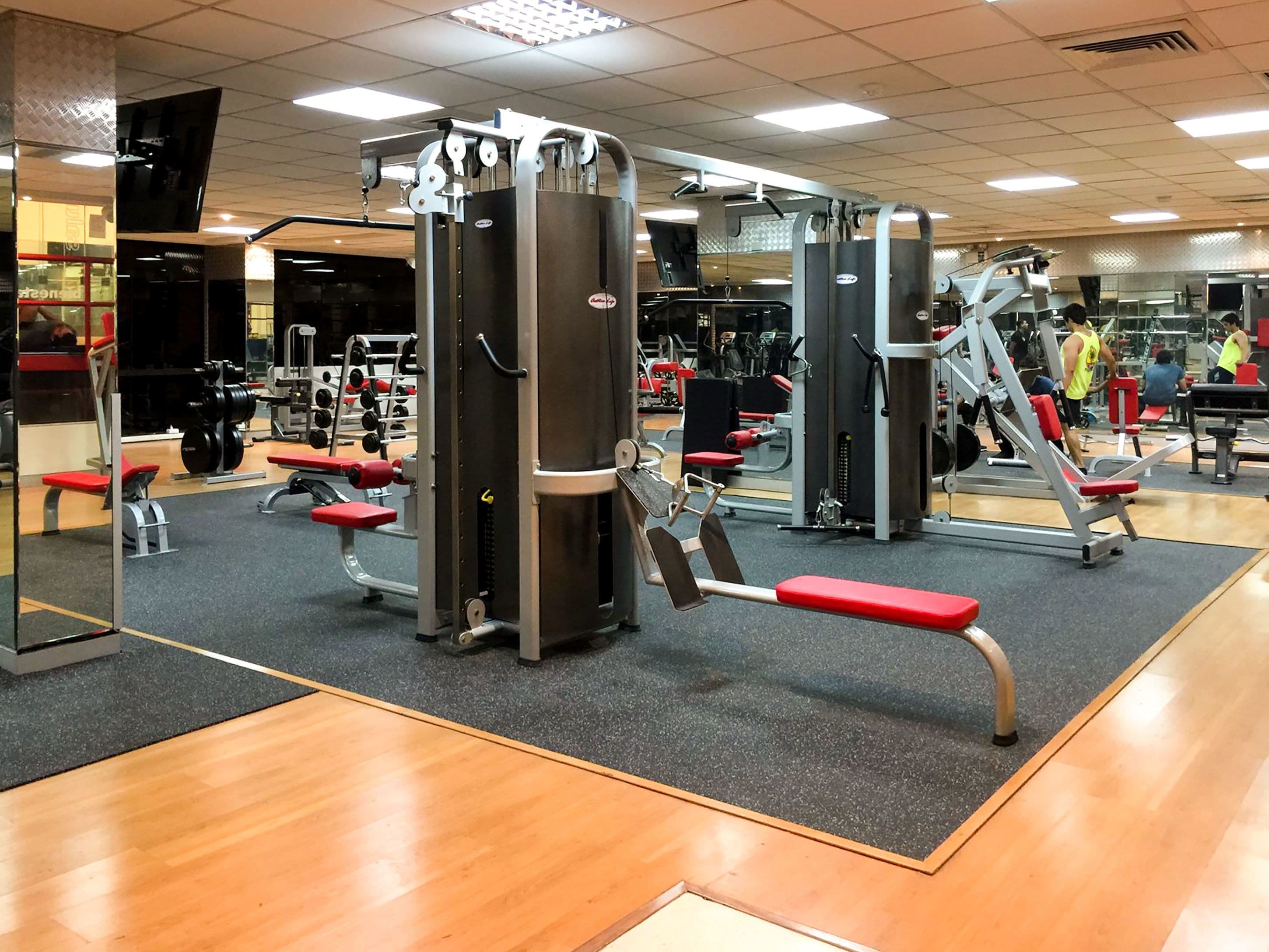 A gym with various exercise machines, benches, and mirrors.