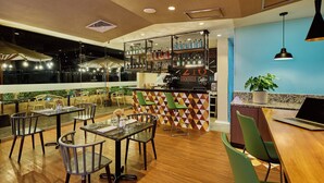 A restaurant with a bar area, wooden flooring, and green chairs. - Estelar Apartamentos Bellavista (Lima)