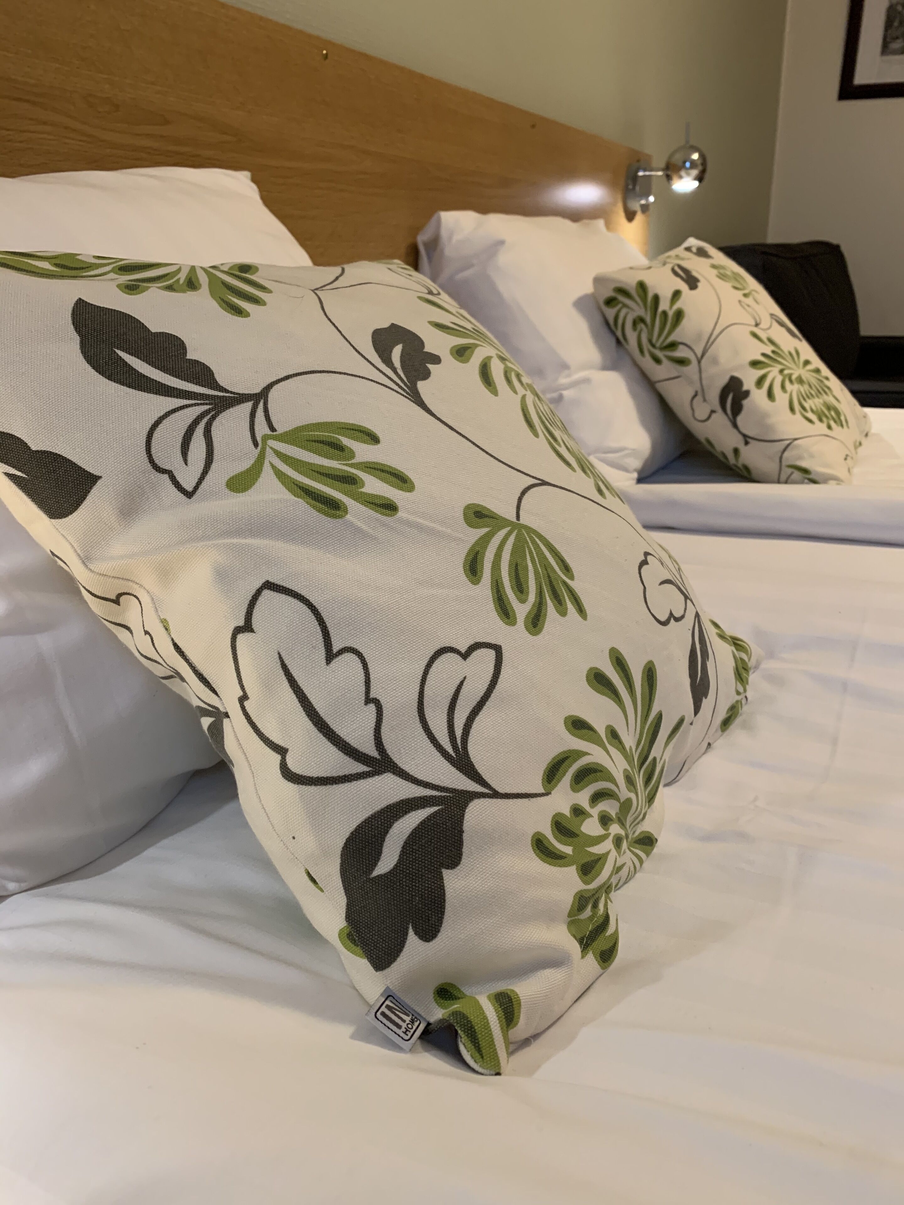 A bed with white bedding and decorative pillows with a floral pattern.