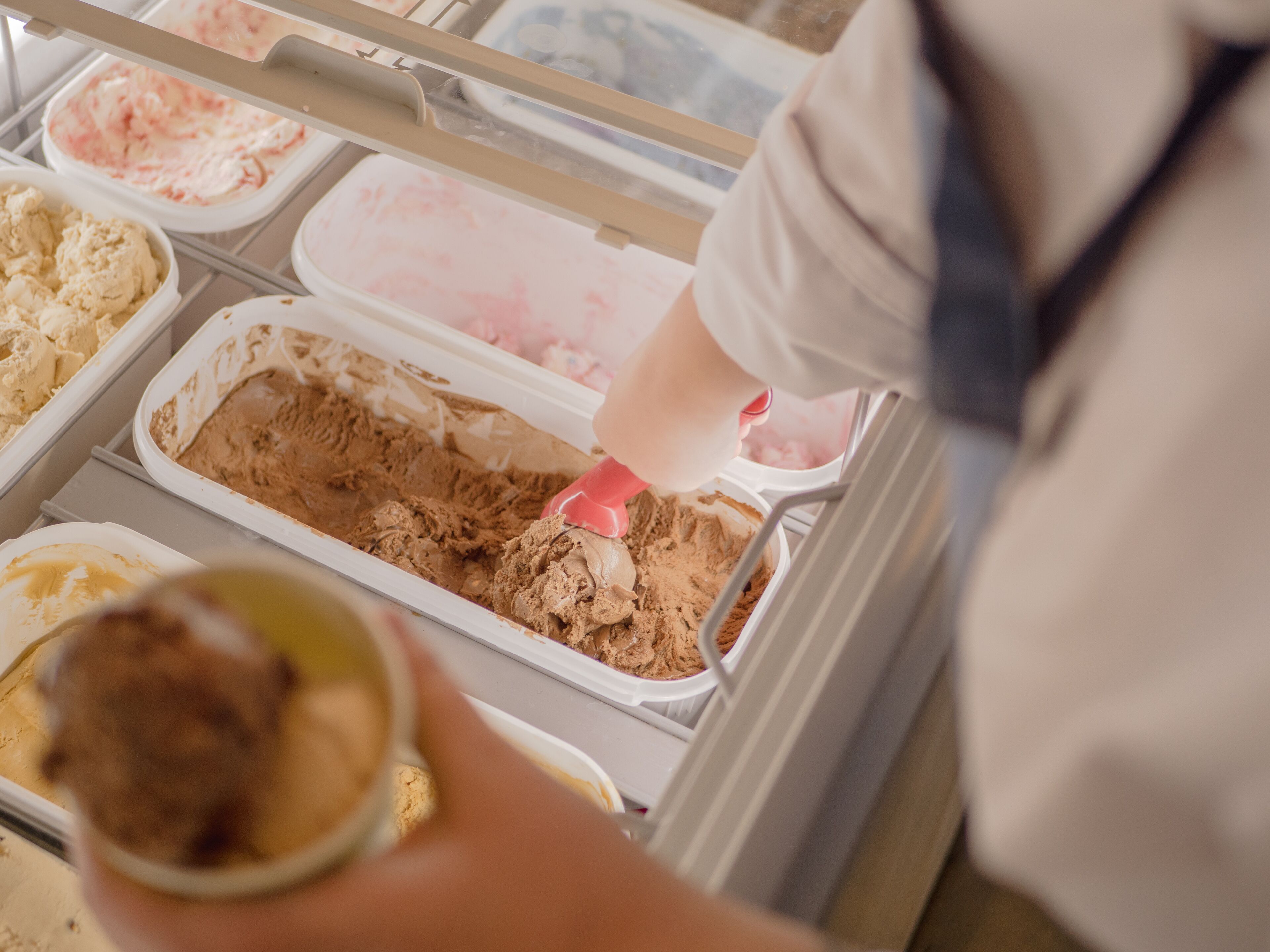 A person scooping ice cream from a container.