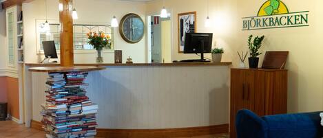 A reception area with a stack of books, a clock, and a sign reading "Björkbacken".