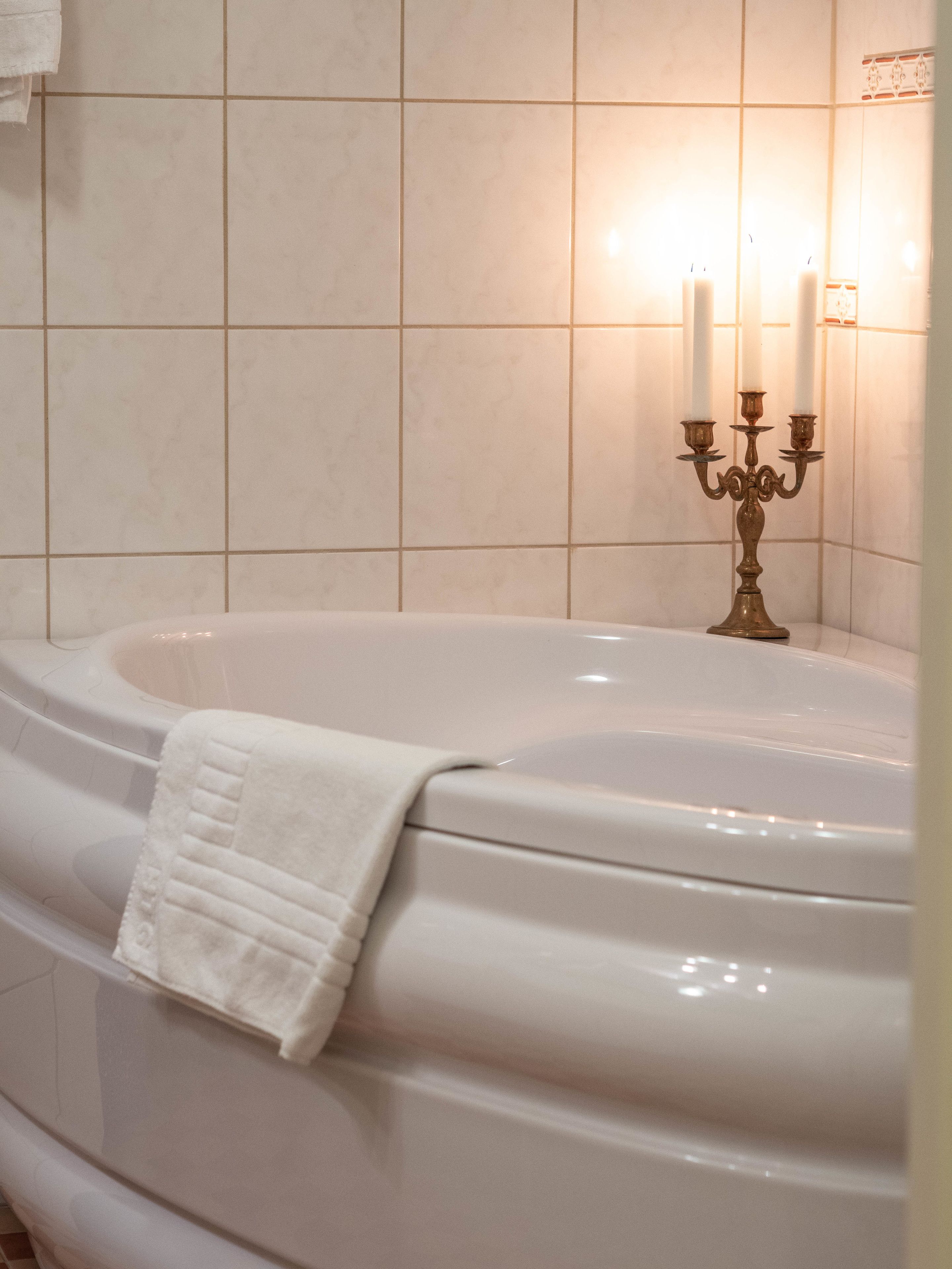 Un baño con una bañera grande, un candelabro con velas y una toalla en la bañera.