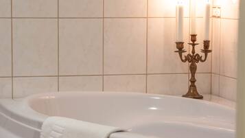 Un baño con una bañera grande, un candelabro con velas y una toalla en la bañera.