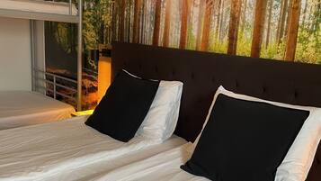 A room with a bunk bed and a single bed, both with white bedding and black pillows.