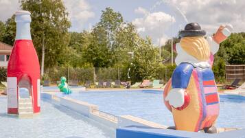 A water park with a large inflatable figure, a red water slide, and lounge chairs.