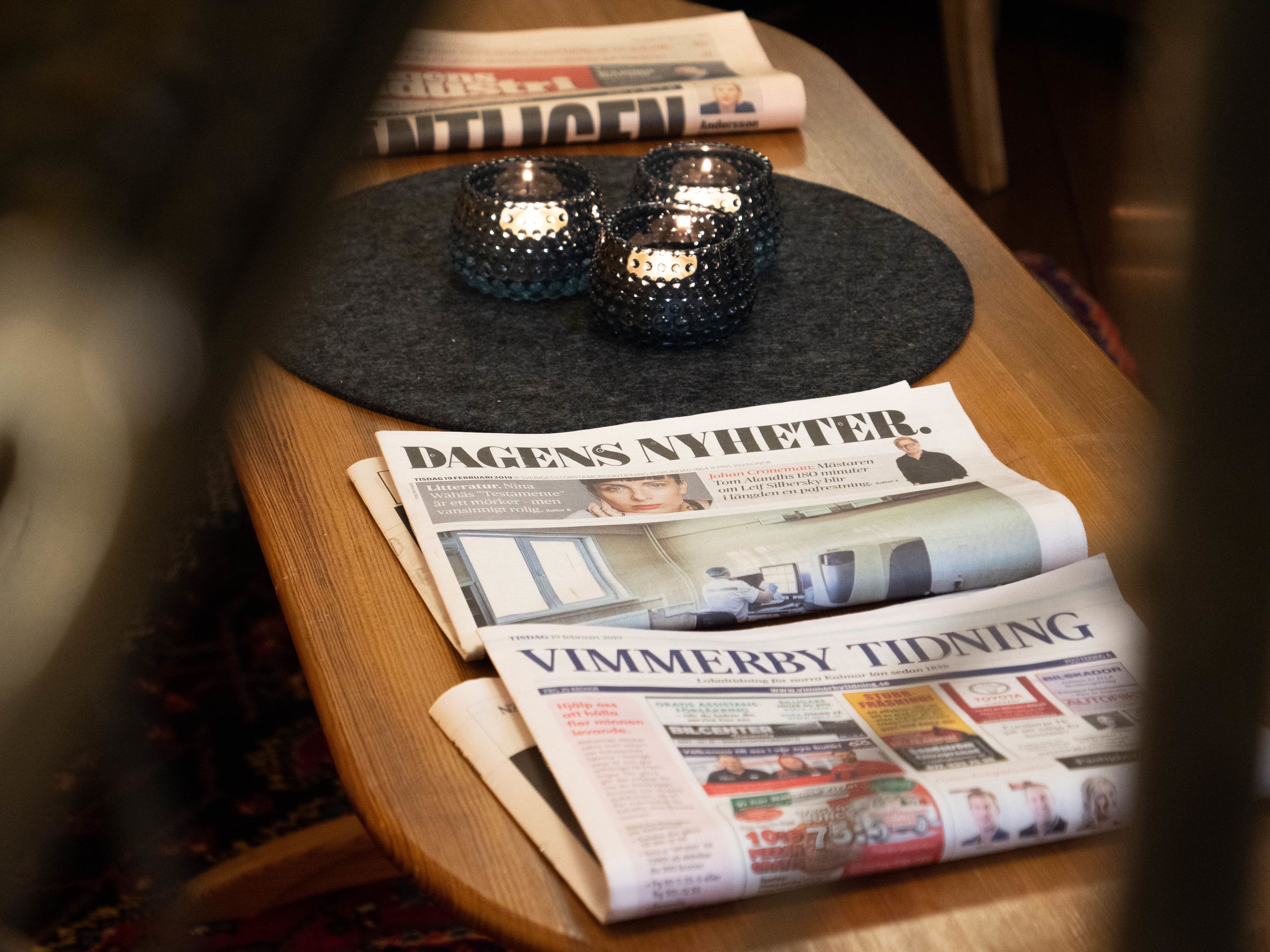 A wooden table with newspapers and two decorative candle holders.