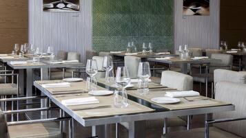 Un ristorante moderno con tavoli e sedie disposti con cura e una parete decorata con un motivo a fantasia verde.