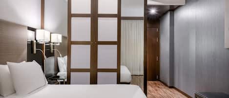 Habitación de hotel con una cama grande, lámparas de noche, un escritorio y una silla.