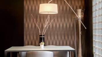A modern dining area with a table, chairs, a vase with branches, and a floor lamp.