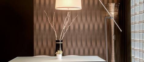A modern dining area with a table, chairs, a vase with branches, and a floor lamp.