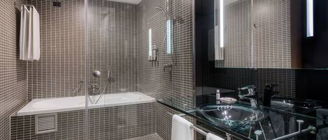 Un bagno moderno con doccia vetrata, lavabo in vetro e un grande specchio.