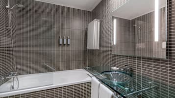 Une salle de bain moderne avec une baignoire entourée de parois en verre, un espace de douche vitré et un grand miroir.