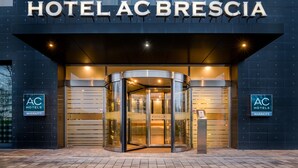 A modern hotel entrance with a revolving door and a sign reading "HOTEL AC BRESCIA". - AC Hotel Brescia by Marriott (Brescia)