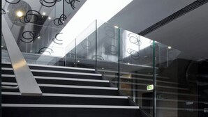 A modern staircase with glass railings and a geometric light fixture. - AC Hotel Brescia by Marriott (Brescia)