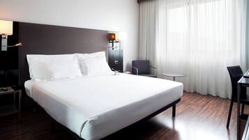 Una habitación de hotel moderna con una cama grande, un escritorio, una silla y una mesita.