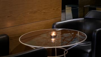 A round glass table with a metal frame, surrounded by black leather chairs.