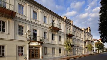 Ein historisches Gebäude mit einer Bäckerei im Erdgeschoss, mehreren Balkonen und klassischer Architektur.