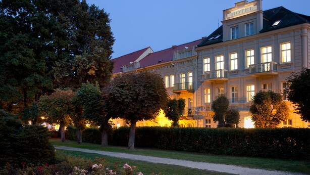 A large, historic building with a prominent "HOTEL" sign, surrounded by well-maintained gardens and trees. - Badenia Hotel Praha (Frantiskovy Lazne)
