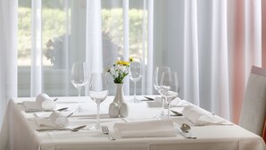 A table set for dining with white tablecloth, glassware, and a vase with flowers. - Badenia Hotel Praha (Frantiskovy Lazne)