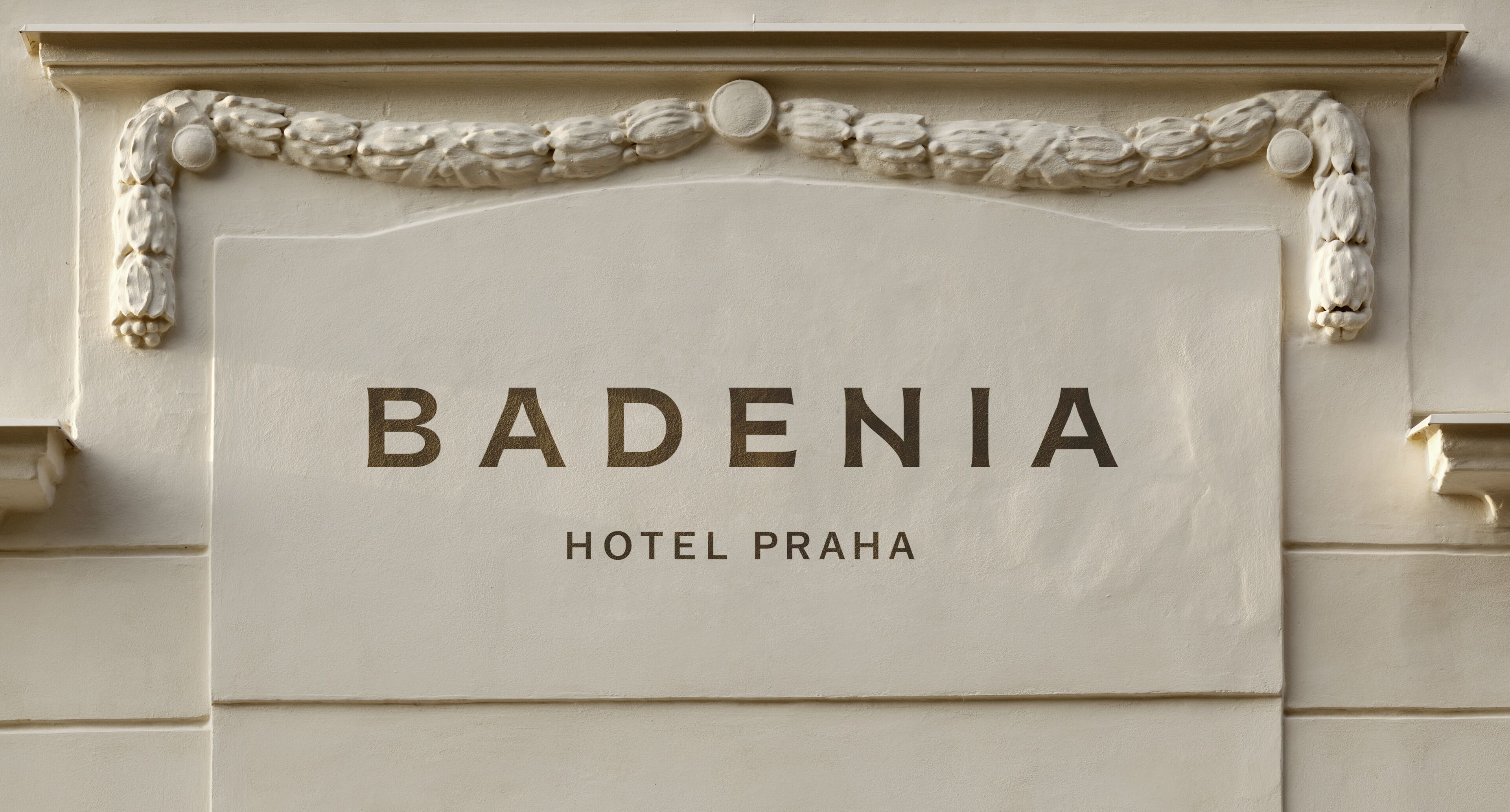 A sign for the Bademia Hotel Praha, featuring a classic architectural design with decorative moldings.
