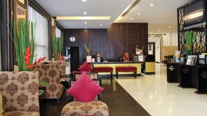 A hotel lobby with patterned sofas, a reception desk, and decorative plants. - FuramaXclusive Sukhumvit (Bangkok)