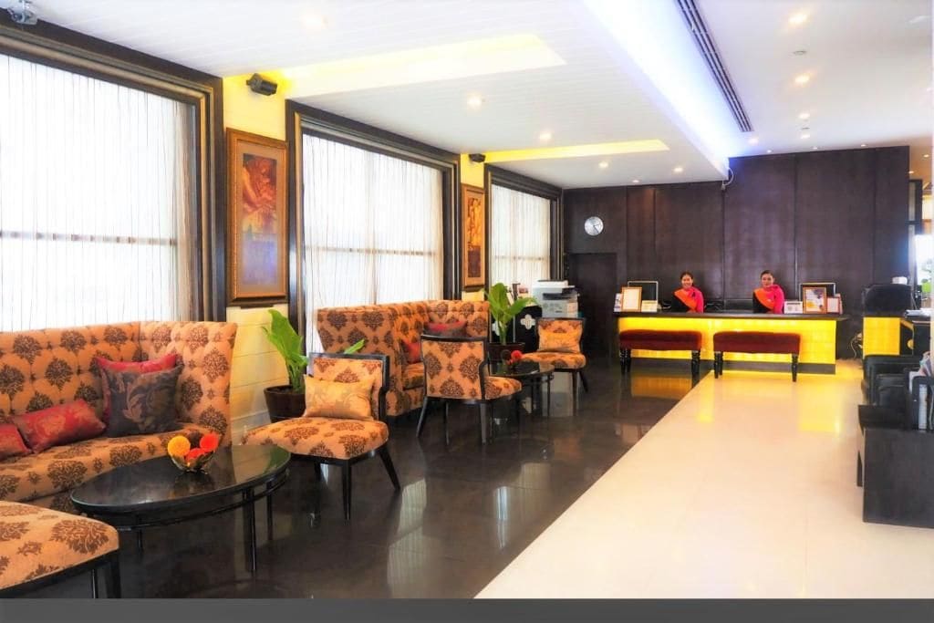 Rebedor d'hotel amb taulell de recepció, zona de seients i grans finestres.