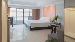 A modern hotel room with a large bed, a desk, a chair, a small table, and a plant. - FuramaXclusive Sukhumvit (Bangkok)